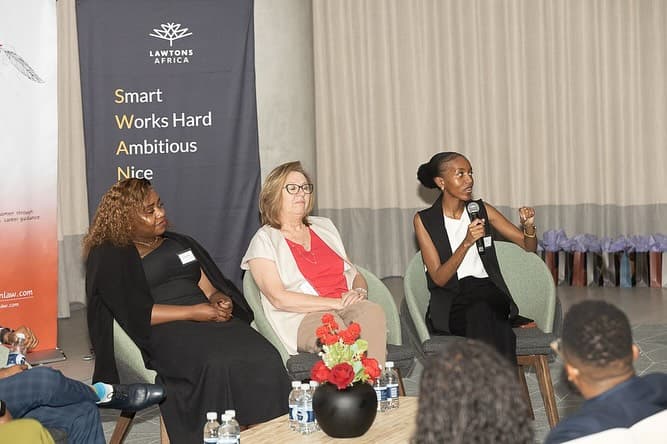 Women in a legal consultation setting, discussing documents around a table.